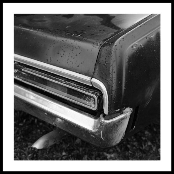 black and white film photograph of a rear tail pipe and tail light light on an old ford zf fairlane
